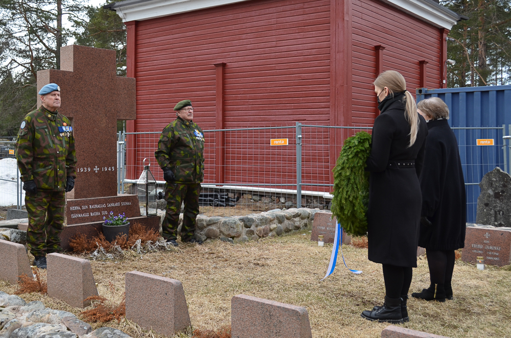 Reserviläisten liiton seppeleen laskivat Kempeleen seurakunnan Anna Keränen ja Kempeleen kirkkovaltuuston puheenjohtaja Kaisu Juvani. Naiset ovat pysähtyneet parin metrin päähän muistomerkistä hiljaisuudessa, Keränen pitää seppelettä kädessään.